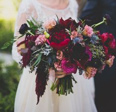 a bride holding a bouquet of flowers in her hands while standing next to the groom