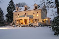 a large white house with lights on in the snow