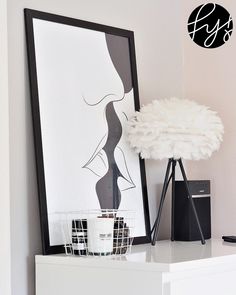 a white vase sitting on top of a dresser next to a framed poster and lamp