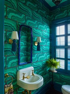 a bathroom with green walls and blue tiles on the wall, along with a gold faucet