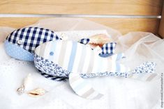 a stuffed fish is sitting on a bed with white and blue fabric around it's neck