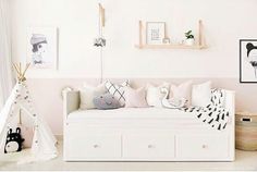 a white day bed sitting in a living room next to a wall with pictures on it