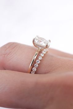 a woman's hand with a diamond ring on top of her finger and an engagement band