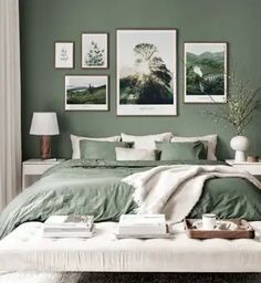 a bedroom with green walls and pictures on the wall above the bed, along with two lamps