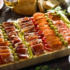 many different types of meats and vegetables on a wooden cutting board, including asparagus