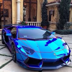 a blue sports car is parked in front of a house with an iron door and windows