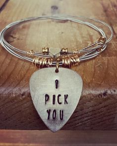 a bracelet with a guitar pick and i pick you written on the front in silver