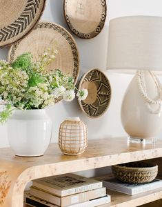 a table topped with a vase filled with flowers next to a wall mounted wicker basket