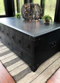 an old trunk is sitting on top of a rug in front of a large window