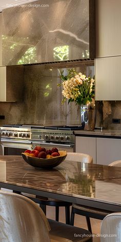 a bowl of fruit sitting on top of a wooden table next to a stovetop oven