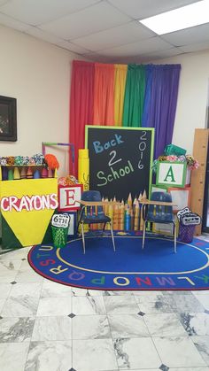 a classroom decorated in rainbow colors with chalkboards and crayons on the floor