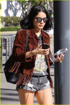 a woman in short shorts is looking at her cell phone while walking down the street