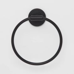 a black towel ring on a white surface with a circular handle and an oval hole in the middle