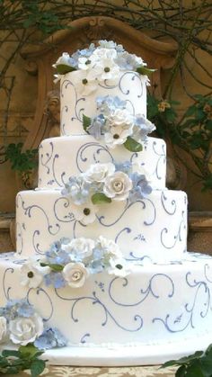 a three tiered wedding cake with blue and white flowers