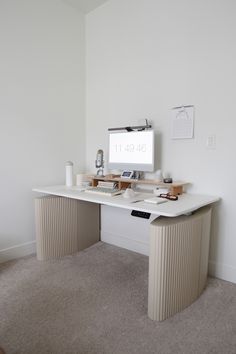 a desk with a computer monitor and keyboard on it in front of a white wall