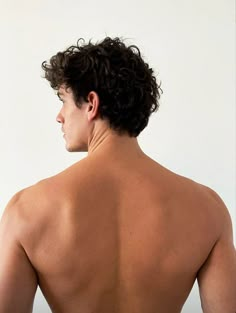 the back of a man with no shirt on, looking at something in the distance