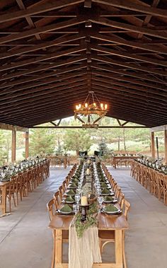 an outdoor dining area with tables, chairs and chandeliers set up for a formal function