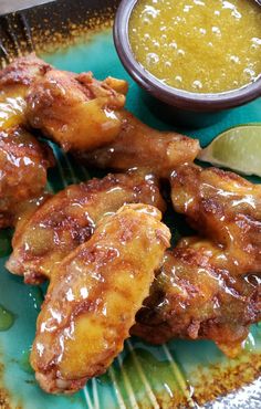 chicken wings with dipping sauce on a blue plate next to a lime slice and spoon