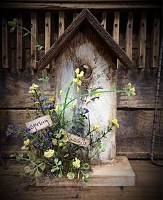 a birdhouse with flowers in front of it