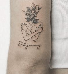 a woman's arm with a tattoo on it that reads, still growing and flowers