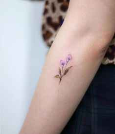 a woman's arm with purple flowers on the left side of her arm,