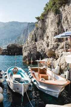 two boats tied up to the dock near some rocks