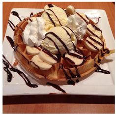 a waffle topped with bananas and ice cream drizzled in chocolate sauce