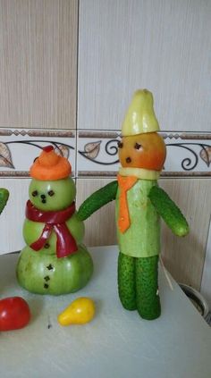 two vegetables are made to look like people with hats and scarfs, standing next to each other