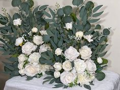 white flowers and greenery are arranged on a table