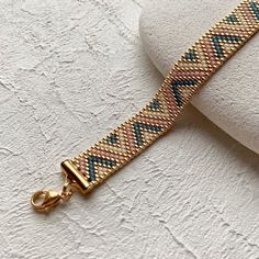 a close up of a bracelet on a white surface with a gold clasp and chain