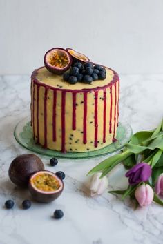 a cake sitting on top of a glass plate next to flowers and an avocado