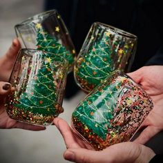 three people holding wine glasses decorated with christmas trees