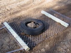 an old tire sitting on the ground next to a chain link fence