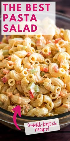 the best pasta salad is in a glass bowl with a pink arrow pointing to it