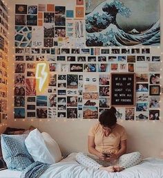 a woman sitting on top of a bed in front of a wall covered with pictures