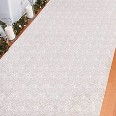 a white table cloth on top of a wooden floor next to candles and vases