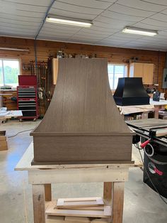 a wooden stove top sitting on top of a table in a room filled with tools