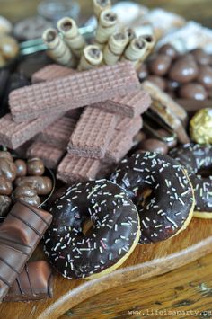 chocolate covered doughnuts and cookies on a wooden platter