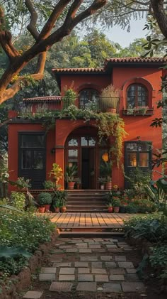 an orange house with lots of plants and trees in the front yard, along with steps leading up to it