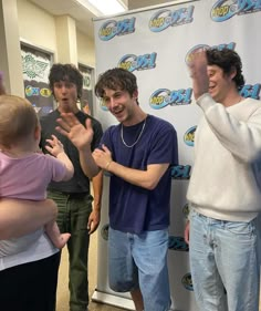 three men and a baby standing in front of a sign