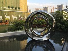 a metal sculpture sitting on top of a black table in front of a tall building