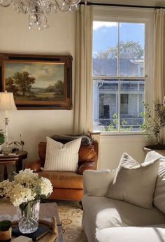 a living room filled with furniture and a chandelier hanging from the ceiling next to a window