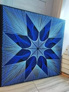 a blue and black painting sitting on top of a wooden floor