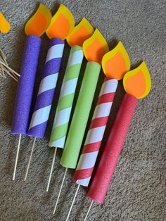 colorful candles are lined up next to each other on the floor with sticks sticking out of them