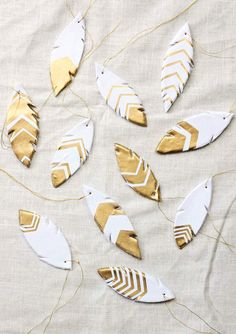 gold and white feathers are hanging on a tablecloth with twine strings in the shape of arrows