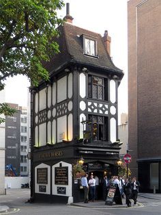 people are standing in front of an old building on the corner with tall buildings behind it