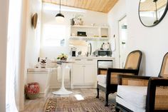 a living room filled with furniture next to a white sink and mirror on the wall