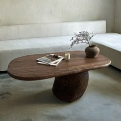 a wooden table sitting on top of a white couch next to a vase filled with flowers