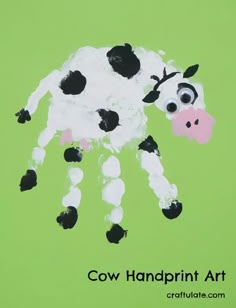 a cow handprint art made with black and white paint on a green paper background