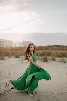 a woman in a green dress is walking on the beach